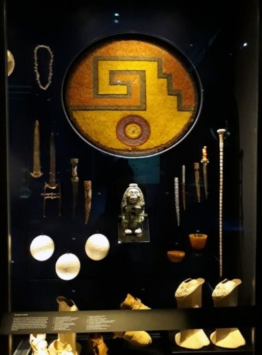 Museum case with a xicalcoliuhqui chimalli at the center, as shown